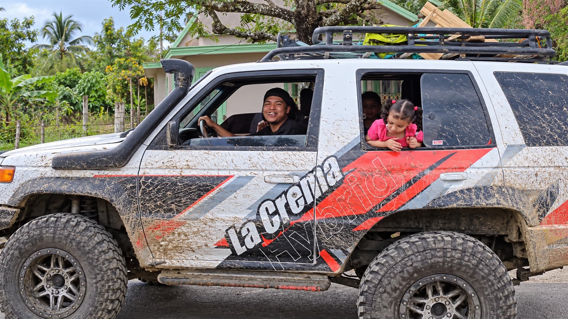 Conductor sonriente y una niña asomada a la ventana de una 4Runner enlodada